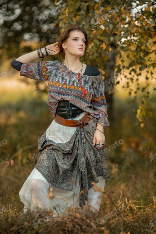 Preview: Young woman in boho style clothes posing in autumn forest
