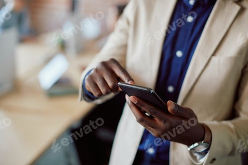 Preview: Close up of black entrepreneur using smart phone in the office.