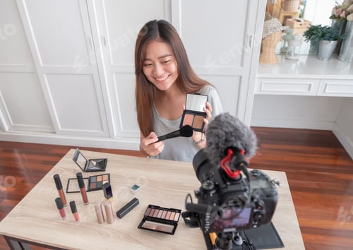 Preview: Asian young female blogger recording vlog video with makeup cosmetic at home