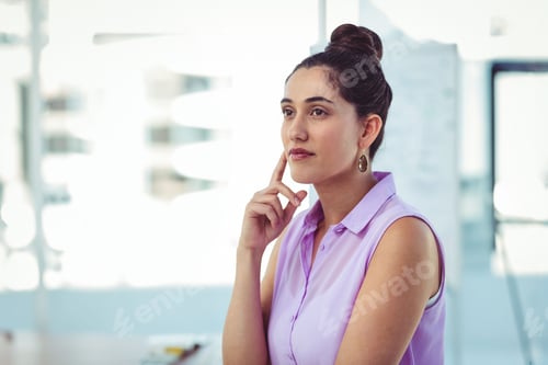 Preview: Woman wearing lavender blouse resting chin on right hand, gazing at desk by whiteboard, copy space