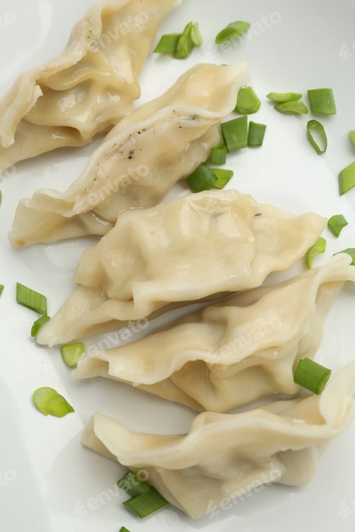 Preview: Tasty boiled gyoza (dumplings) with green onion on plate, top view