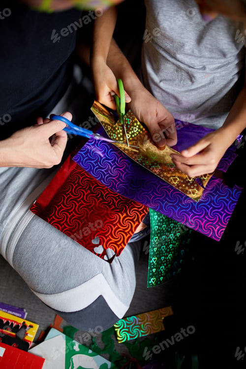 Preview: Daughter and father having fun making craft together at home on the sofa