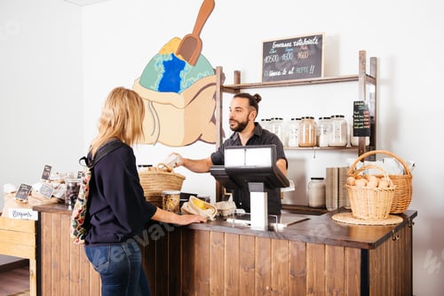 Preview: Cheerful Storekeeper Serving Customer in Bright Grocery Store During Daytime