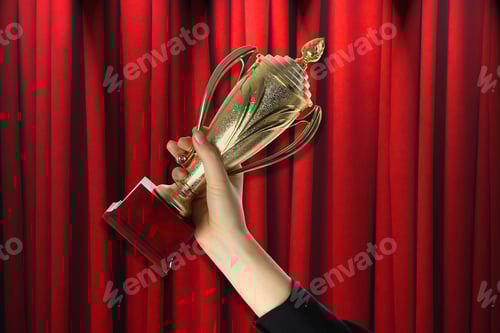 Preview: Woman holding golden trophy against red curtain, closeup