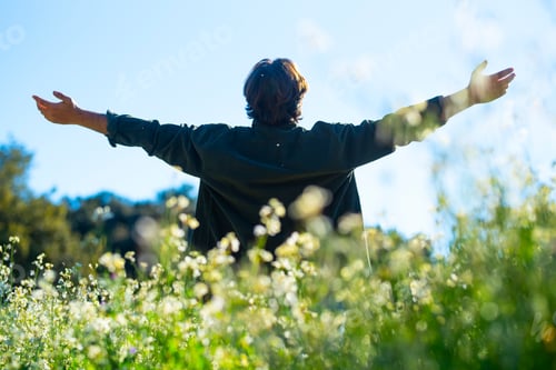 Preview: Back view of man outstretching arms in a green field. Travel destination tourism. Outdoor leisure