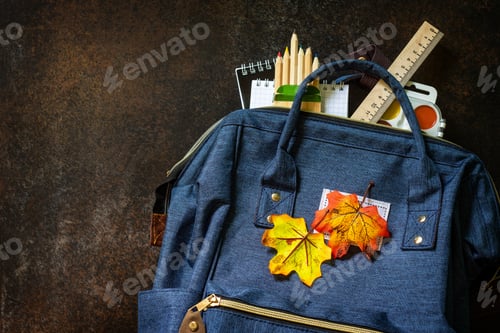 Visualização: Conceito de volta às aulas. Material escolar com mochila azul na mesa.