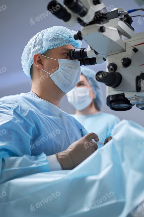 Preview: Male Surgeon Operating Microscope during Surgical Procedure