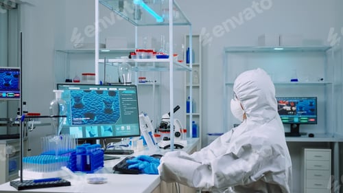 Preview: Chemist typing on pc and coworker analysing microscope slides