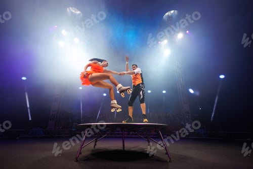 Preview: Young pair of acrobats, man and woman, on roller skates perform in a circus on a small round stage.