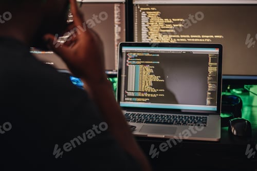 Preview: African American man sitting at computer desk looking at computer code, programming, developer