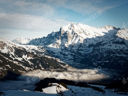 Preview: Snow-covered mountains with clear blue sky and valley clouds