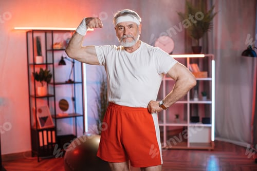 Preview: Caucasian older man showing his muscular biceps at home