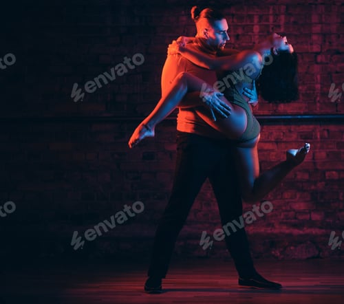 Preview: Beautiful couple dancing in a night club. Dancers performing in the dark with illumination