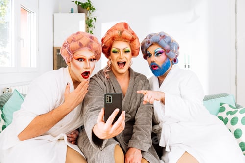Preview: Surprised drag queens using mobile phone on a living room