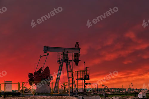 Preview: Oil drill rig and pump jack at sunset background.
