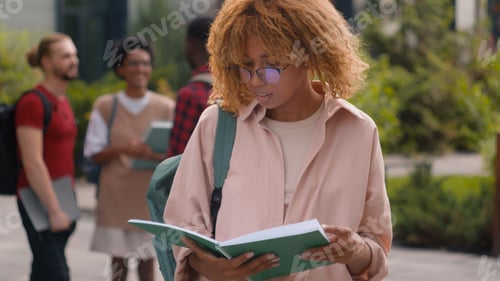 Preview: Happy African American smiling student girl reading book textbook woman female schoolgirl in city