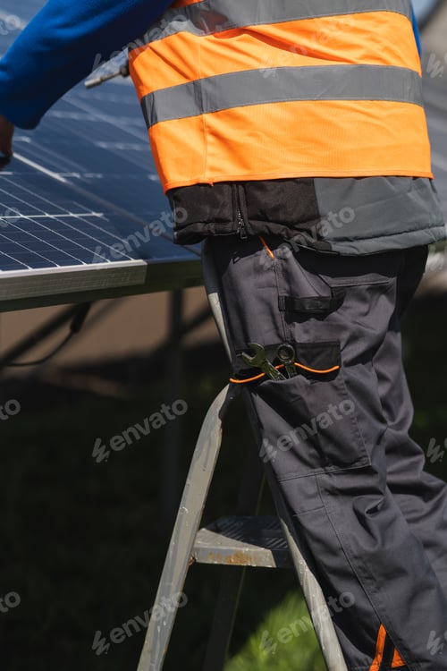 Preview: Male engineer who installs and maintains solar panels stands on a stepladder