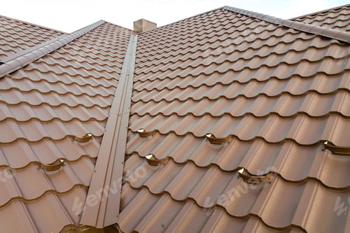 Preview: Detail of a house roof surface covered with brown metal tile sheets.