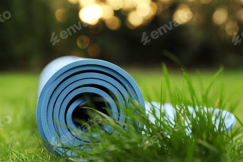 Preview: Bright karemat or fitness mat in fresh green grass outdoors, closeup