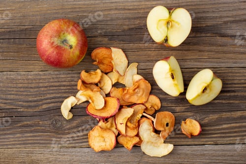 Preview: A pile of dried slices of apples and fresh ripe apples on wooden background.