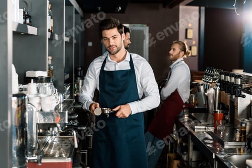 Preview: handsome barista in apron making coffee at workplace