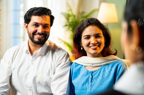 Preview: Indian young happy couple discussing with female corporate consultant, closeup home meeting