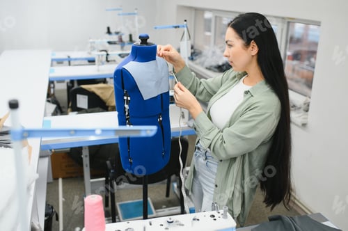 Preview: Positive young woman sewing with professional machine at workshop.