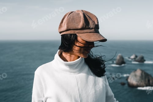 Preview: caucasian young woman in white sweater and corduroy hat looking at the ground calm and relaxed near