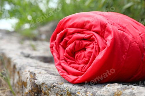 Preview: Rolled sleeping bag outdoors on sunny day, closeup