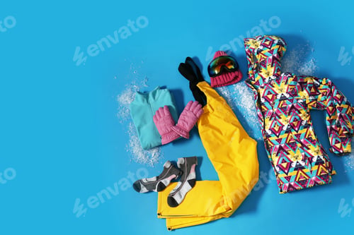 Preview: Stylish winter sport clothes on light blue background, flat lay