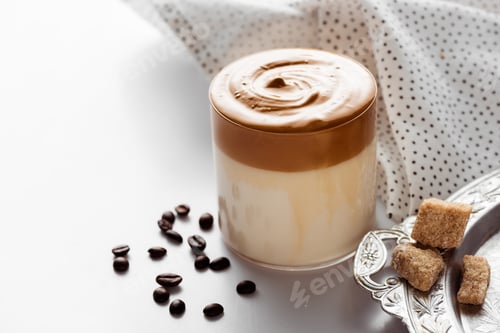 Preview: Delicious Dalgona Coffee in Glass Near Coffee Beans, Brown Sugar on Silver Platter And Napkin