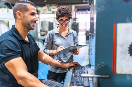 Engineer and manager talking while using computer in a factory