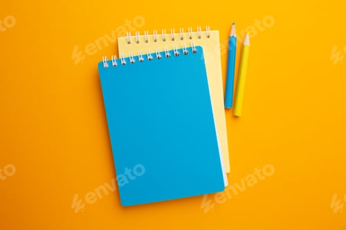 Preview: Yellow and blue notebook with pencils on a yellow background
