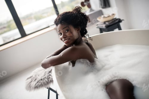 Preview: Slim young sexy woman chilling in foamy bath standing near window