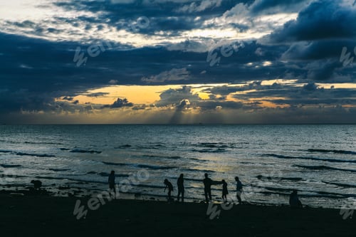 Preview: Group of people enjoying scenic sunset at the beach