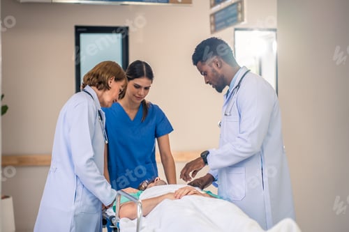 Preview: Group of diverse doctors moving seriously injured patient in hospital.