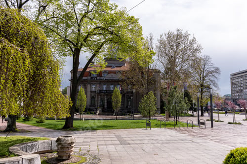 Preview: Beautiful shot of the Nis Town Hall behind sunny trees and green land in downtown Nis, Serbia