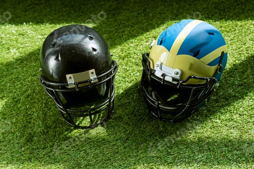 Preview: high angle view of american football safety helmets on green grass