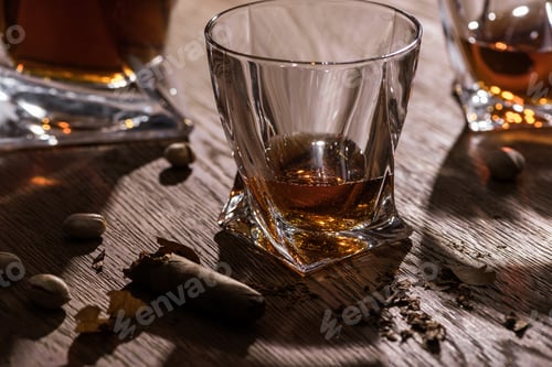 Preview: Brandy in glasses and decanter with cigar and pistachios on wooden table