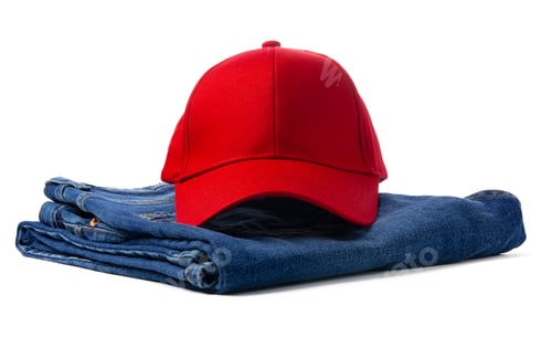 Preview: Red Baseball Cap Resting Atop Folded Blue Denim Jeans Against a White Background