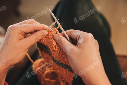 Preview: Close-up of the hands of an unrecognizable person knitting a sweater with two needles