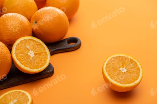 Preview: ripe delicious cut and whole oranges on wooden cutting board on colorful background