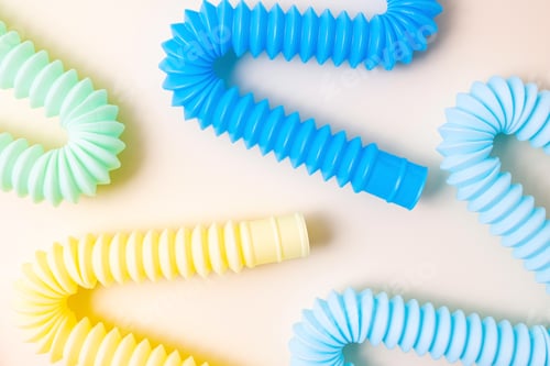 Preview: Trendy kids toys pastel colorful pop-tube n baby toddler hands on beige background.