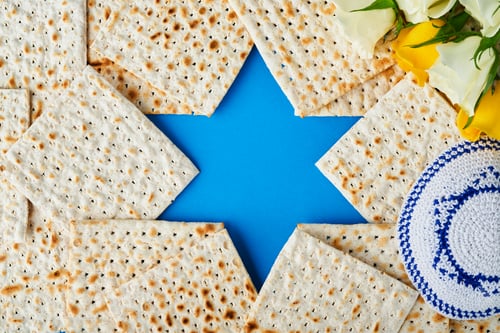 Preview: Passover celebration concept. Blue Star of David made from matzah, white and yellow roses, kippah an