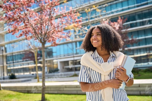 Preview: Happy African American girl student standing in university campus looking away.