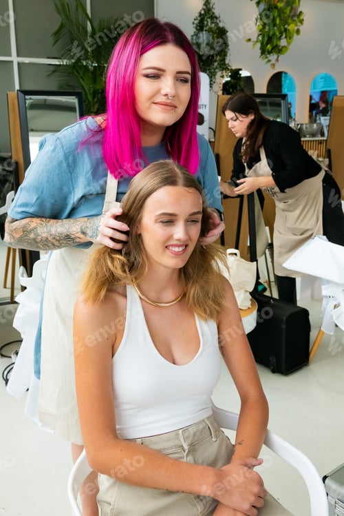 Preview: Professional stylist working on young female model in hair salon