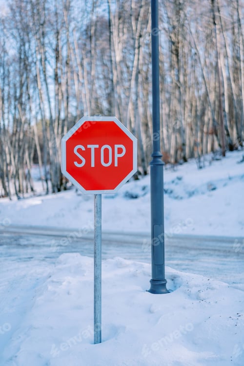 Preview: Road sign near a pillar on a snowy road in the park. Caption: Stop