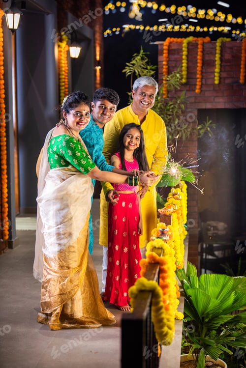 Preview: Indian young family with kids celebrating Diwali festival with sparklers in gallery
