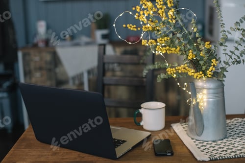 Preview: Workplace at loft, laptop, mobile, a cup of tea and vase with flowers on the wooden table
