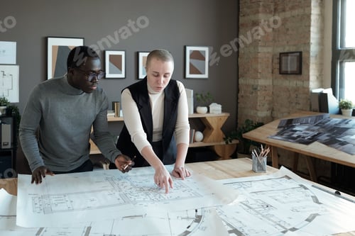 Preview: Two confident engineers in smart casualwear discussing blueprint